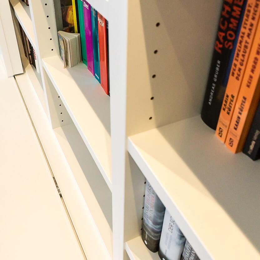 Maßgefertigte Bücherwand mit verborgenem Stauraum Nahaufnahme einer individuell angefertigten Bücherwand mit dezenten Fächern und verstecktem Stauraum, die stilvolles Design mit Funktionalität verbindet.