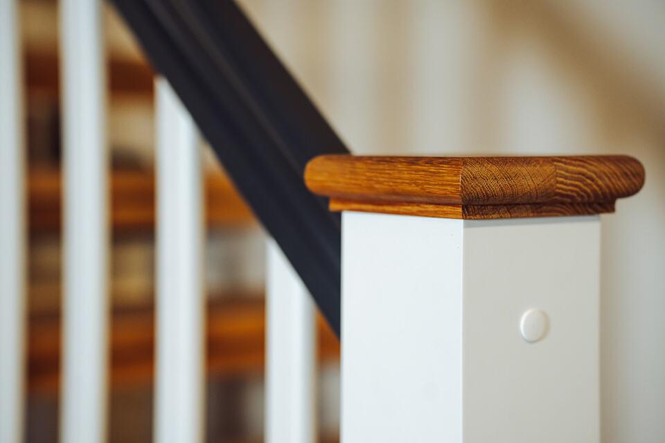 weißer Treppenpfosten mit schwarzem Handlauf und holz Veredelung