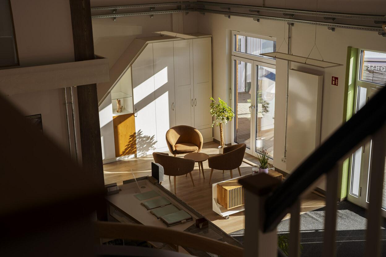 runder Tisch mit Sesseln zur Planung von Möbel und Innenausbauten im Hintergrund befindet sich ein weißer Dachschrägenschrank in einem lichtdurchfluteten IDEEN REICH