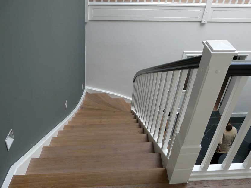 Abwärtsblick auf eine elegante Treppe mit Holzstufen und einem kontrastierenden weißen Geländer