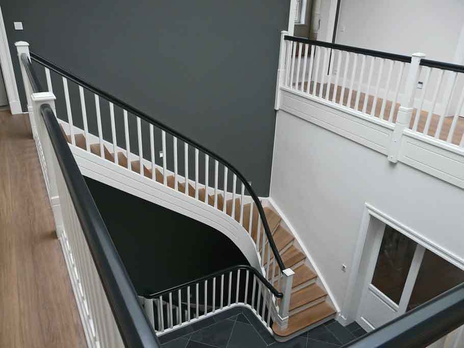 Blick auf ein stilvolles Treppenhaus mit weißem Geländer und dunklen Stufen