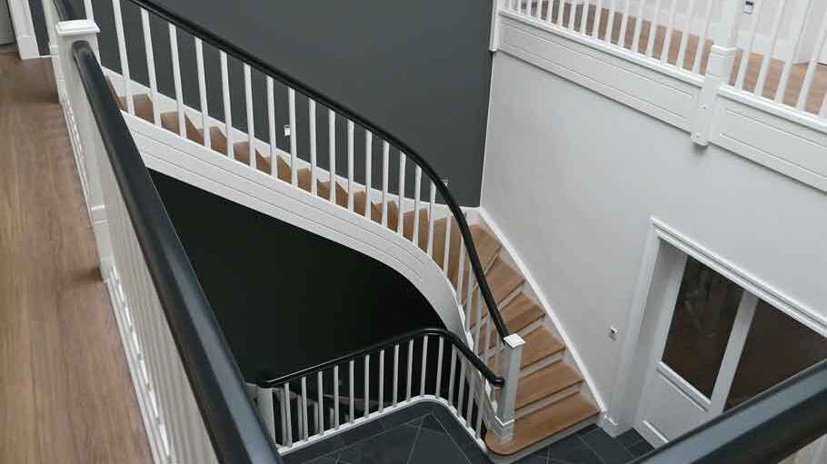 Elegantes Treppenhaus mit geschwungenem Geländer Blick auf ein stilvolles Treppenhaus mit weißem Geländer und dunklen Stufen