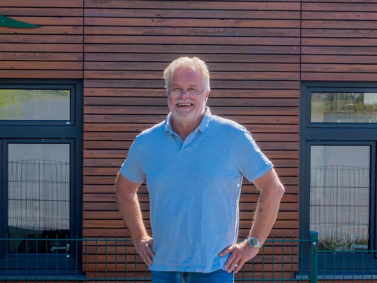 Thomas Jenning steht vor dem IDEEN REICH, welches eine braune Holzfassade aufweist