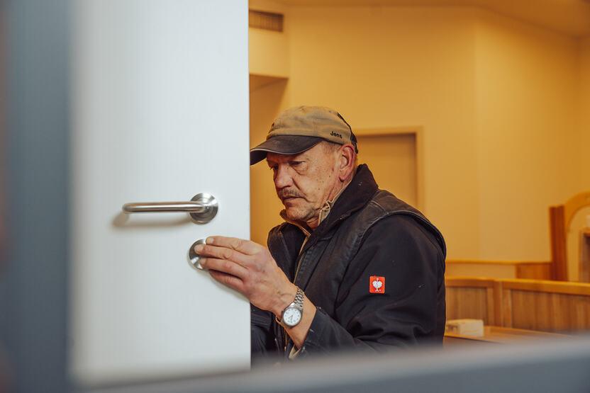 Mitarbeiter in dunkler Kleidung in einem hellen Raum bei der Reparatur einer wei&szlig;en T&uuml;r