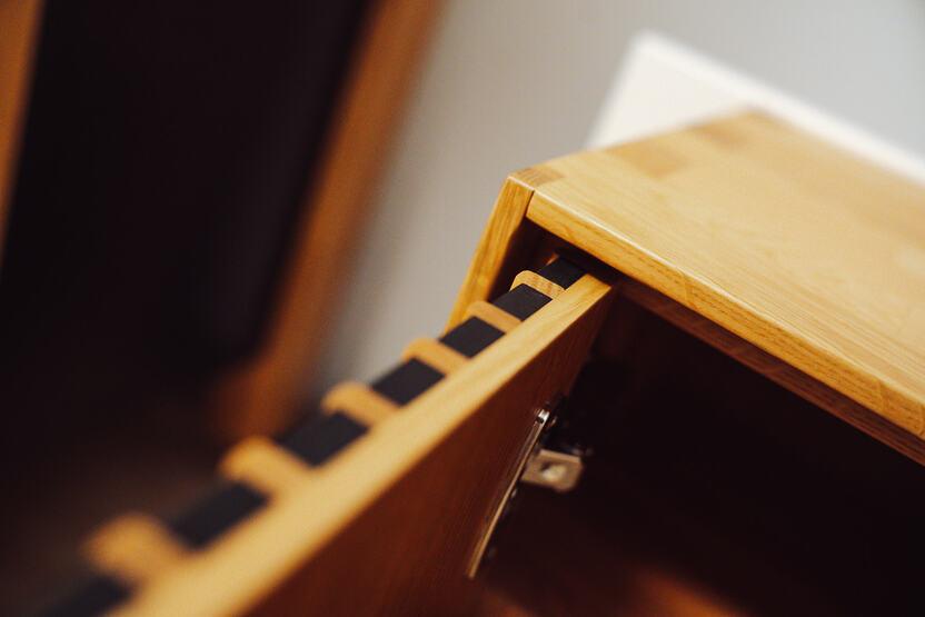 abgebildet ist ein Eichenholz M&ouml;belst&uuml;ck mit schwarzen Akzenten und einer Zinkenverbindung zu dem ist auch ein Schnier zu erblicken