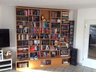 Ein großes braunes Bücherregal, bestückt mit vielen Büchern