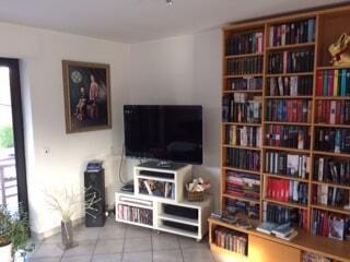 Eine weiße Kommode mit einem Fernseher und ein großes braunes Bücherregal mit vielen Büchern