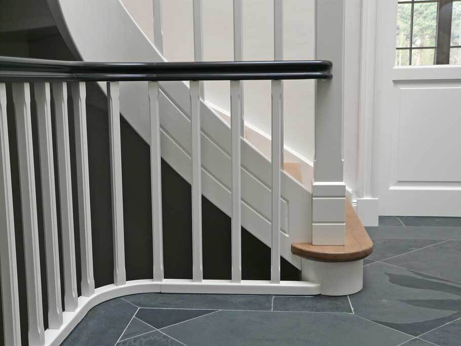 Geschwungene Treppe mit wei&szlig;em Gel&auml;nder, schwarzer Handlauf und eleganter Sitzplatz unten