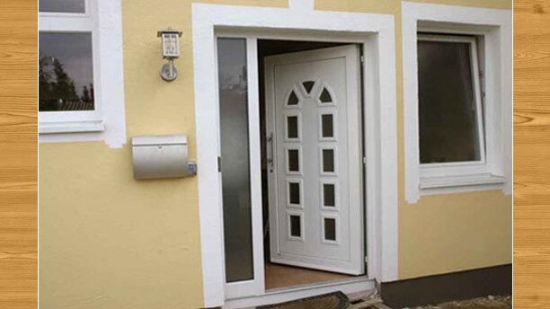 Traditionelle weiße Haustür mit Seitenteil Klassische weiße Haustür mit Glasfenster und Seitenteil an einem gelben Haus mit Holzverkleidung.