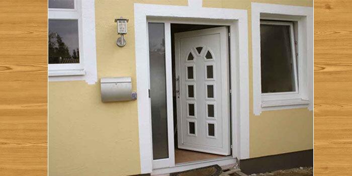 Klassische wei&szlig;e Haust&uuml;r mit Glasfenster und Seitenteil an einem gelben Haus mit Holzverkleidung.