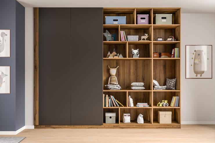 Individuell gestalteter Schrank nach Maß in einem Kinderzimmer. Eleganter, dunkler Schrank nach Maß neben einem offenen Regal mit Spielzeug und Büchern, harmonisch in das Ambiente eines Kinderzimmers eingefügt.