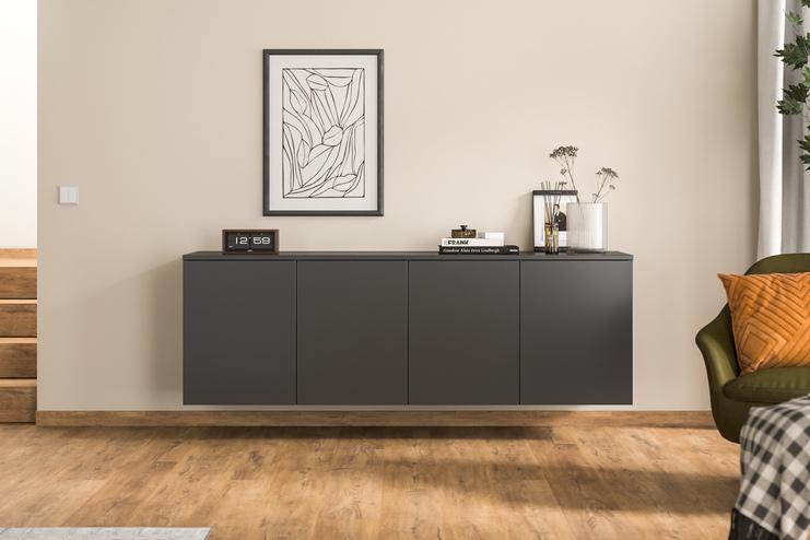 Maßgefertigtes Hängeboard in modernem Wohnzimmer Ein maßgeschneidertes Hängeboard in Anthrazit ergänzt den Wohnraum, stilvoll unter einem abstrakten Gemälde und neben einer grünen Samtsessel platziert.